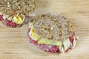 Raw burgers and salad on a wooden background