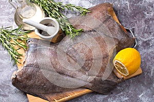 Raw butchered flounder on a cutting board with herbs and spices.