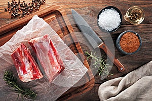 Raw calf short rib on white cooking paper and wooden cutting table