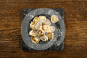 Raw cappelletti pasta on board with flour
