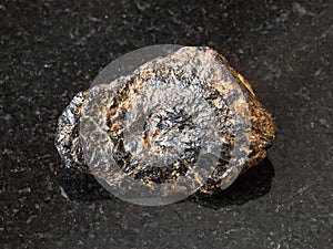 Raw Cassiterite Tin ore stone on black