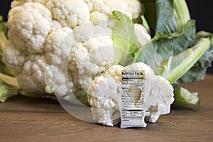 Raw cauliflower head and floret with nutritional fact label on w