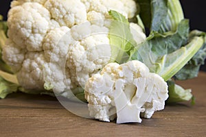 Raw cauliflower head and floret on wooden board