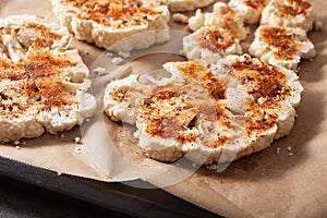 Raw cauliflower steaks with spice on baking tray. plant based meat substitute