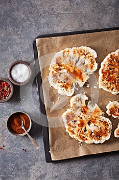 Raw cauliflower steaks with spice on baking tray. plant based meat substitute