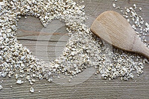 Raw cereals in heart form with brown spoon