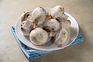 Raw champignon mushrooms in a plate. Fresh vegetables for cooking.