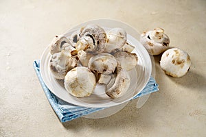 Raw champignon mushrooms in a plate. Fresh vegetables for cooking.