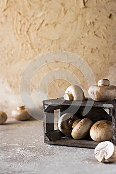 Raw champignons on a rustic wooden box