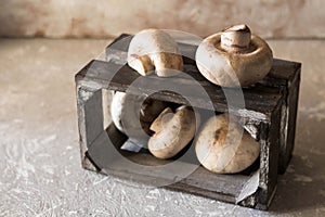 Raw champignons on a rustic wooden box