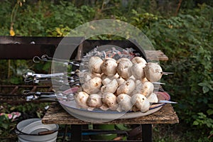 Raw champignons strung on a metal skewer for frying