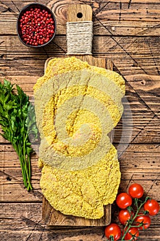 Raw chicken Breaded Weiner Schnitzel. Wooden background. Top view