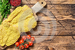 Raw chicken Breaded Weiner Schnitzel. Wooden background. Top view. Copy space