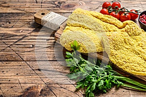 Raw chicken Breaded Weiner Schnitzel. Wooden background. Top view. Copy space