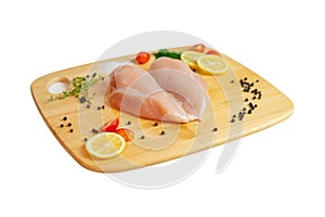 Raw chicken breast fillets and spices on wooden cutting board photo