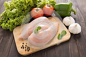 Raw chicken breast fillets and vegetable on wooden background.
