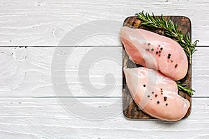 Raw chicken breast fillets on wooden cutting board with herbs and spices