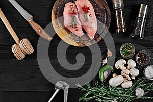 Raw chicken breast fillets on wooden cutting board with herbs and spices. Top view with copy space