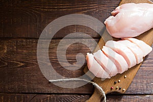 Raw chicken breast fillets on wooden cutting board.