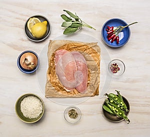 Raw chicken breast with lemon, herbs, pepper, peas, rice, onions, mustard wooden rustic background top view close up