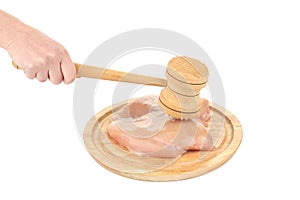 Raw chicken breast and mallet on wooden board.