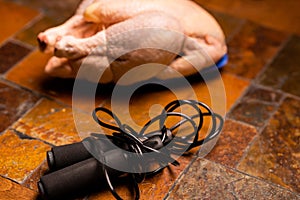 Raw chicken carcass and jump rope on stone background. Sports nutrition, diet concept