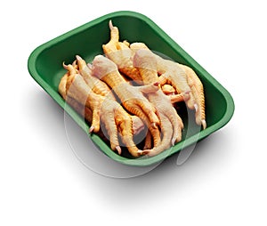 Raw chicken claw in a green tray over white background