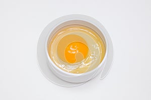 Raw chicken egg in a white cup standing on a white background