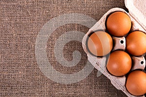 Raw chicken eggs in a basket on a jute cloth background