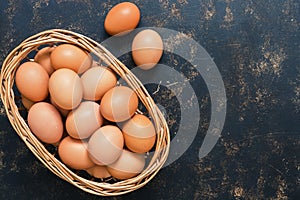 Raw chicken eggs in a basket on a rustic background. Top view, copy space.