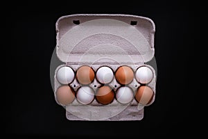 Raw chicken eggs in a package on a black background. Copy space. Space for text