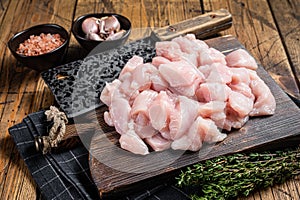 Raw chicken fillet cut into cubes, Uncooked sliced poultry meat, on wooden board. Wooden background. Top view