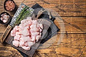 Raw chicken fillet cut into cubes, Uncooked sliced poultry meat, on wooden board. Wooden background. Top view. Copy