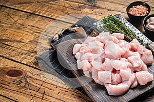 Raw chicken fillet cut into cubes, Uncooked sliced poultry meat, on wooden board. Wooden background. Top view. Copy