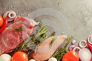 Raw chicken fillet with rosemary,  pork tenderloin, mushrooms, tomato, chili pepper,  onion,   top view on a gray