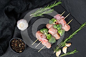 Raw chicken kebab with broccoli. Black background. Top view