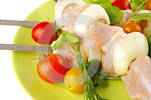 Raw chicken kebabs on dark plate