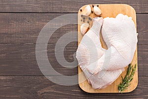 Raw chicken leg on cutting board on wooden background