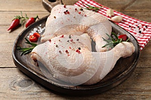 Raw chicken leg quarters and ingredients on wooden table