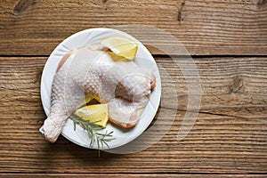 Raw chicken leg on white plate for cooking thai asian food rosemary chicken lemon on wooden food table