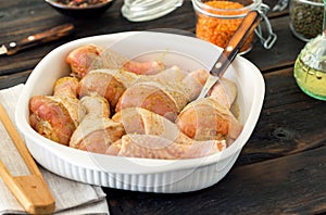 Raw chicken legs in baking dish on wooden table closeup