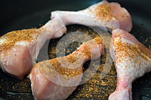 Raw chicken legs cooking on frying pan