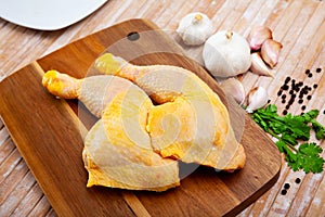 Raw chicken legs on cutting board and plate closeup