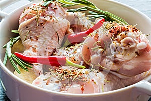 Raw chicken legs (drumsticks) in white baking dish, closeup