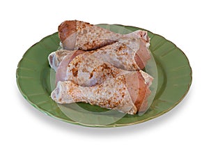 Raw chicken legs on green plate isolated