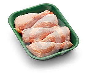 Raw chicken legs in a green tray over white background