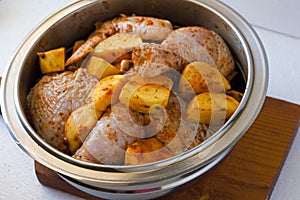 Raw chicken legs with raw potatoes with spices for baking on a wooden table. Meat ingredients for cooking