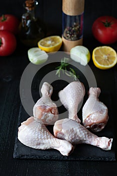 Raw chicken legs on slate plate. on wooden background. closeup