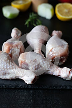 Raw chicken legs on slate plate. on wooden background. closeup