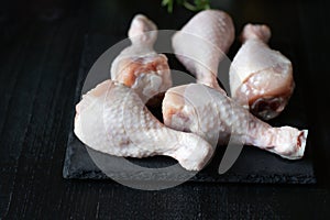 Raw chicken legs on slate plate. on wooden background. closeup